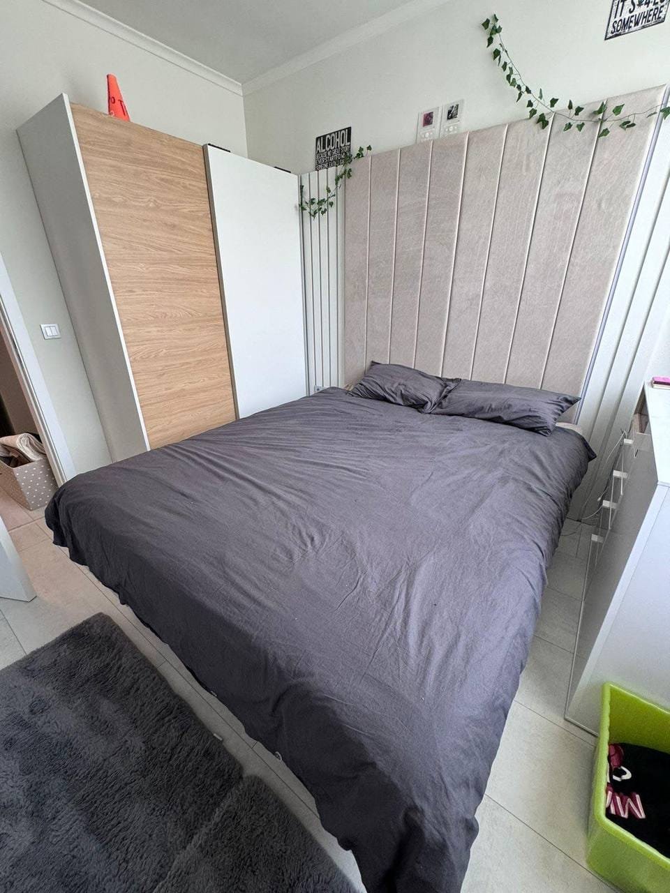 Современная спальня с двуспальной кроватью, светлыми стенами и минималистичной мебелью в Болгарии. уютная атмосфера.