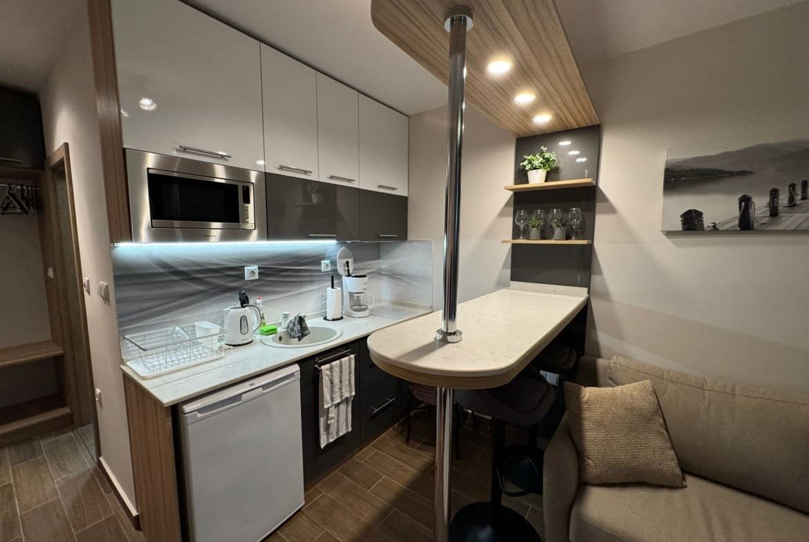 Современная кухня в квартире в Болгарии с белыми шкафами, барной стойкой и техникой, готовая к продаже.