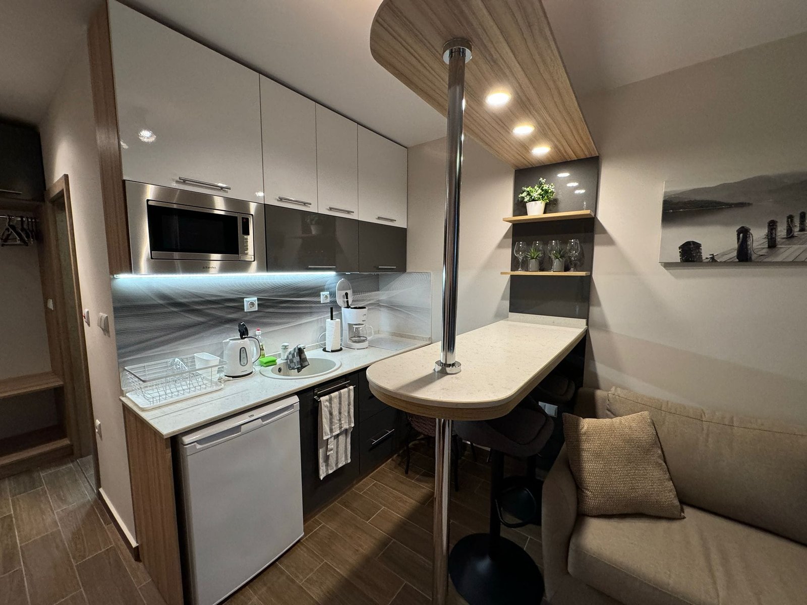 Современная кухня в квартире в Болгарии с белыми шкафами, барной стойкой и техникой, готовая к продаже.