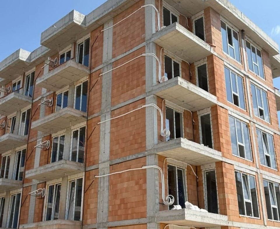 Новая строительная многоквартирная жилое здание в Болгарии с большими окнами и наружными коммуникациями.