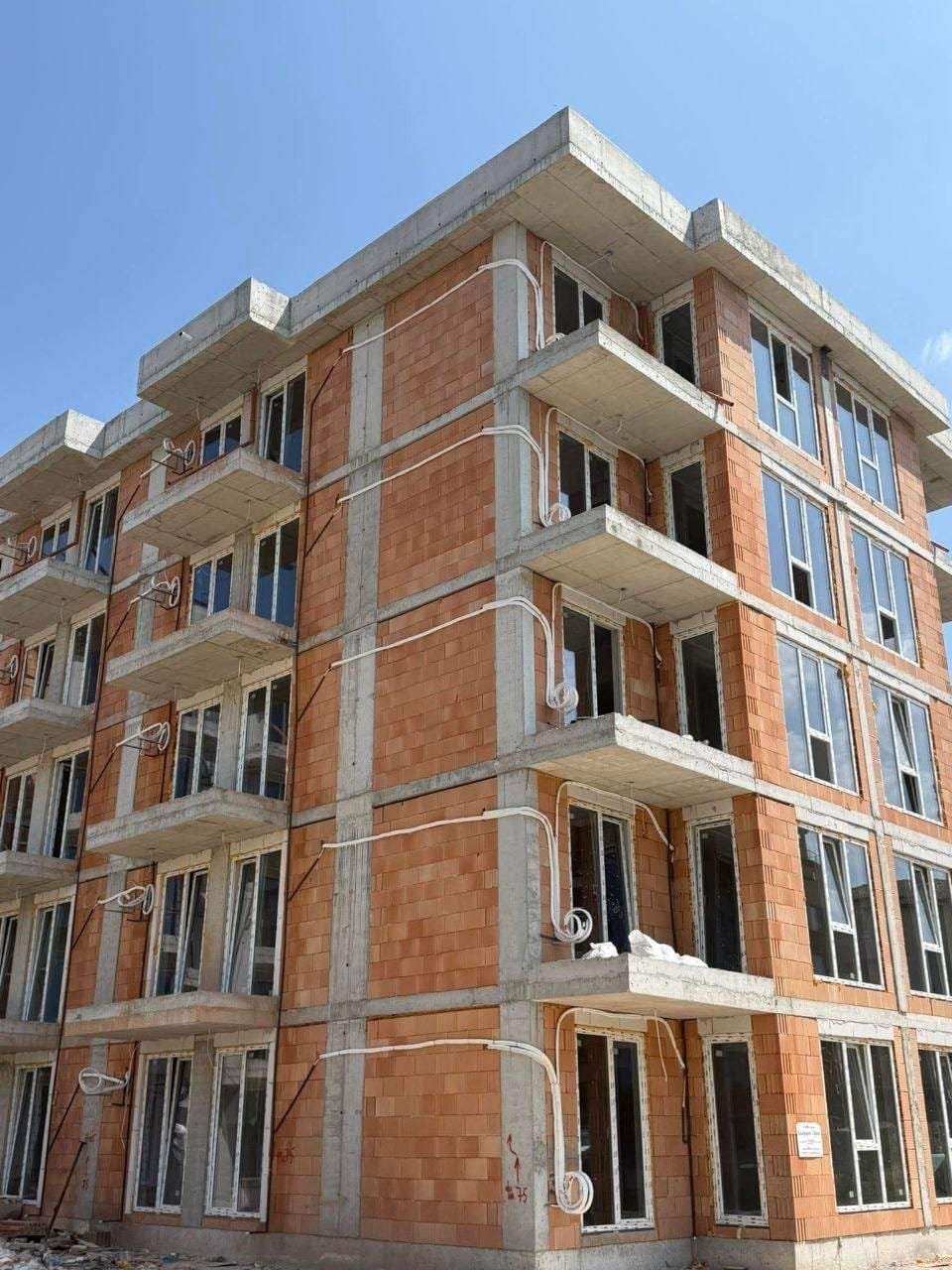 Строящаяся многоквартирная жилое здание с окнами и балконами Новая строительная многоквартирная жилое здание в Болгарии с большими окнами и наружными коммуникациями.