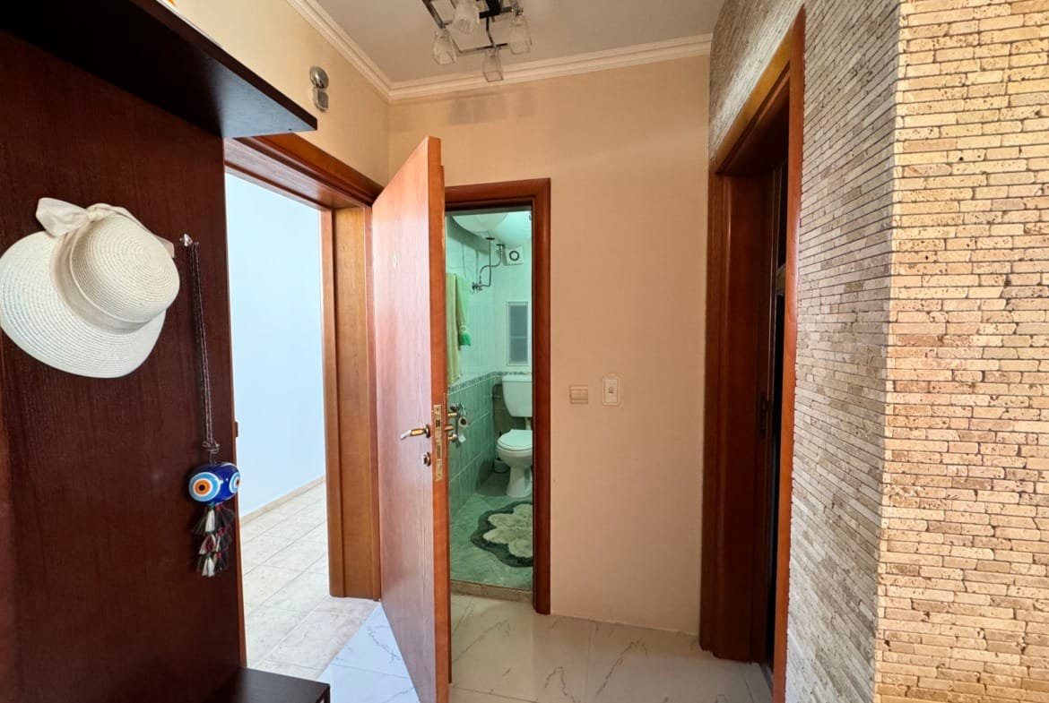 Современный коридор квартиры в Болгарии, с дверью в ванную и отделкой из натурального камня. Функциональное пространство для жилья.