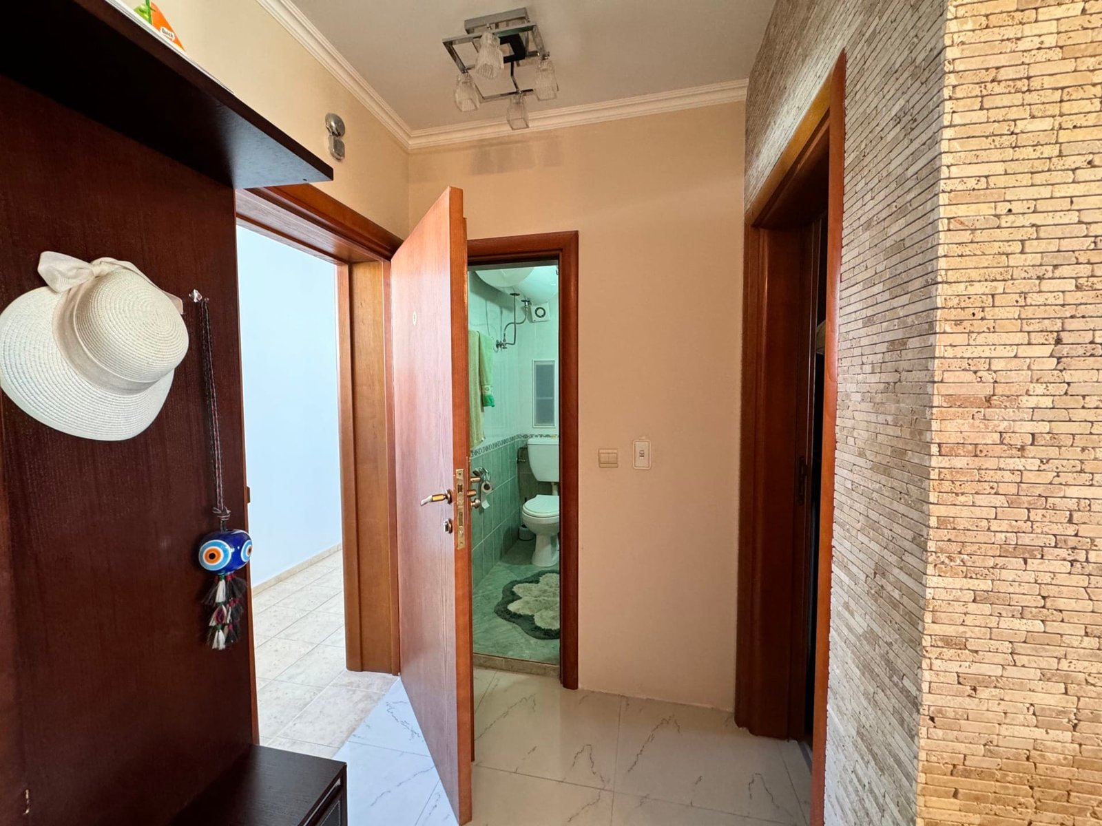 Современный коридор квартиры в Болгарии, с дверью в ванную и отделкой из натурального камня. Функциональное пространство для жилья.