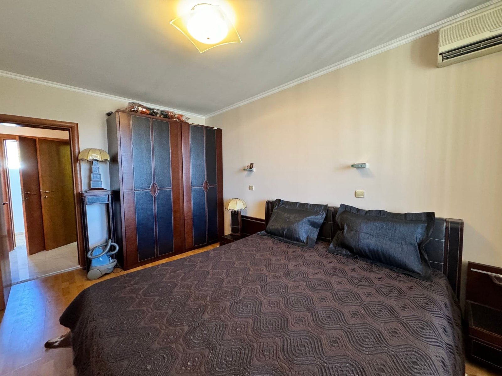 Уютная спальня с двуспальной кроватью, темными тонами, шкафом и светлом, идеально подходящая для отдыха в Болгарии.