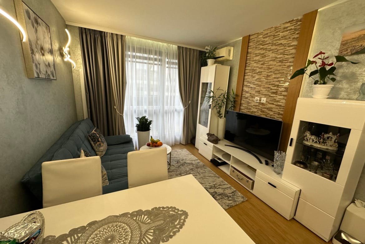 Современный интерьер гостиної с голубым диваном, белыми мебелью и декоративными растениями, гармоничный и светлый.