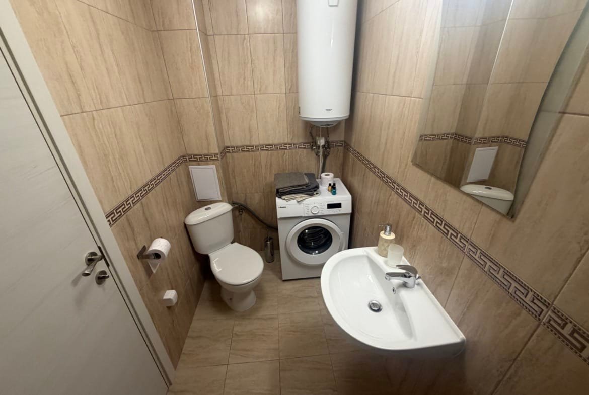 Современная ванная комната с стиральной машиной, унитазом и раковиной, отделка керамикой с нюансами в Болгарии.