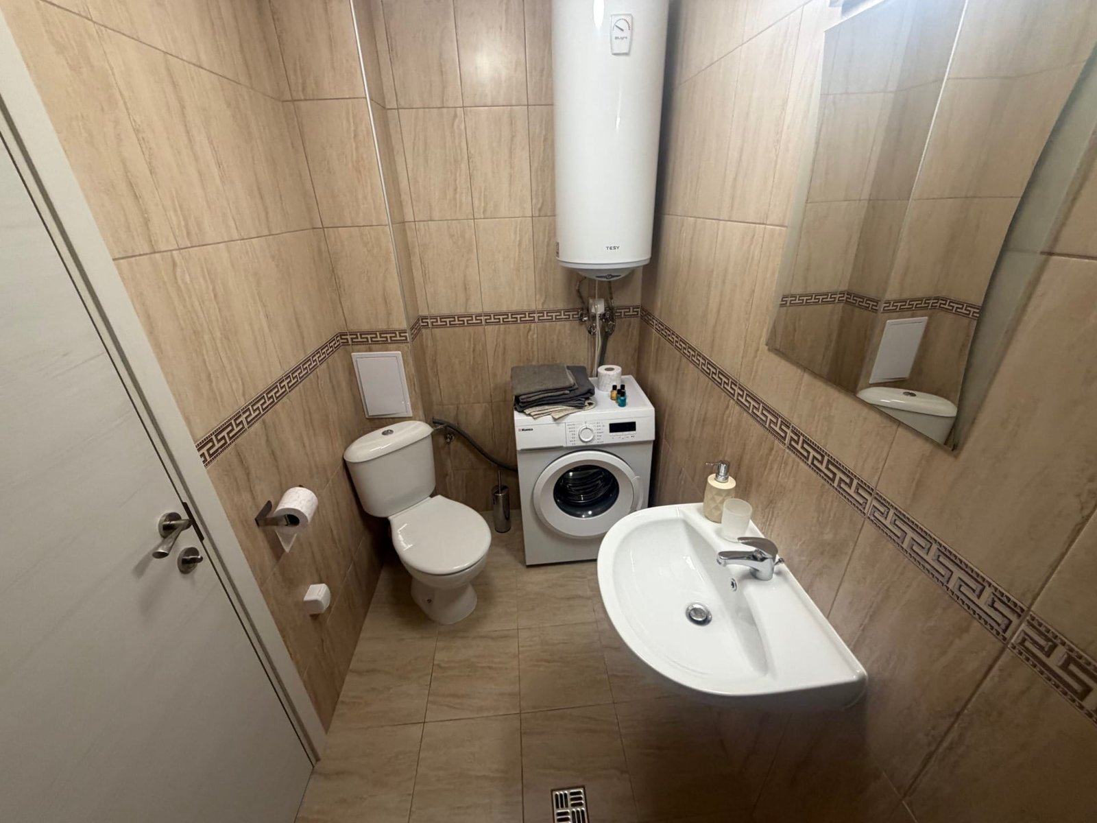 Современная ванная комната с стиральной машиной, унитазом и раковиной, отделка керамикой с нюансами в Болгарии.