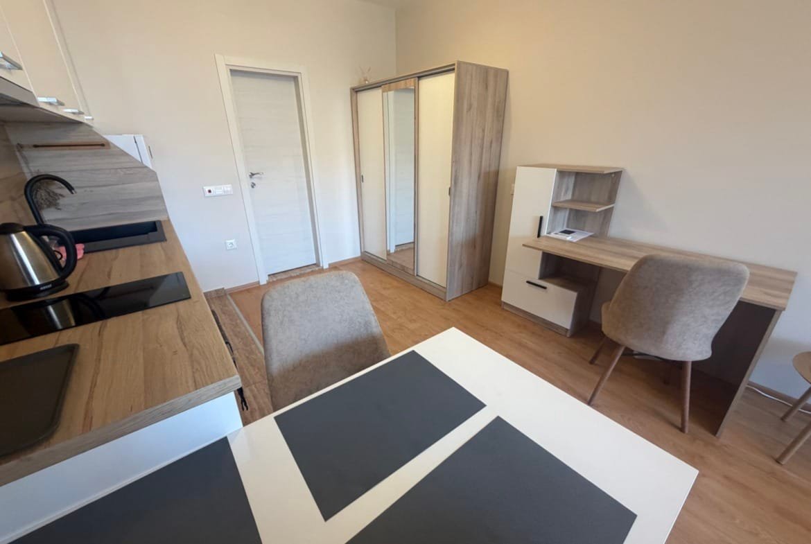 Современная кухня с обеденным столом, комодом и рабочим столом в уютной квартире для продажи в Болгарии.