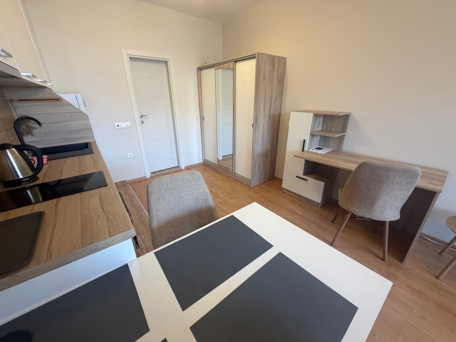 Современная кухня с обеденным столом, комодом и рабочим столом в уютной квартире для продажи в Болгарии.