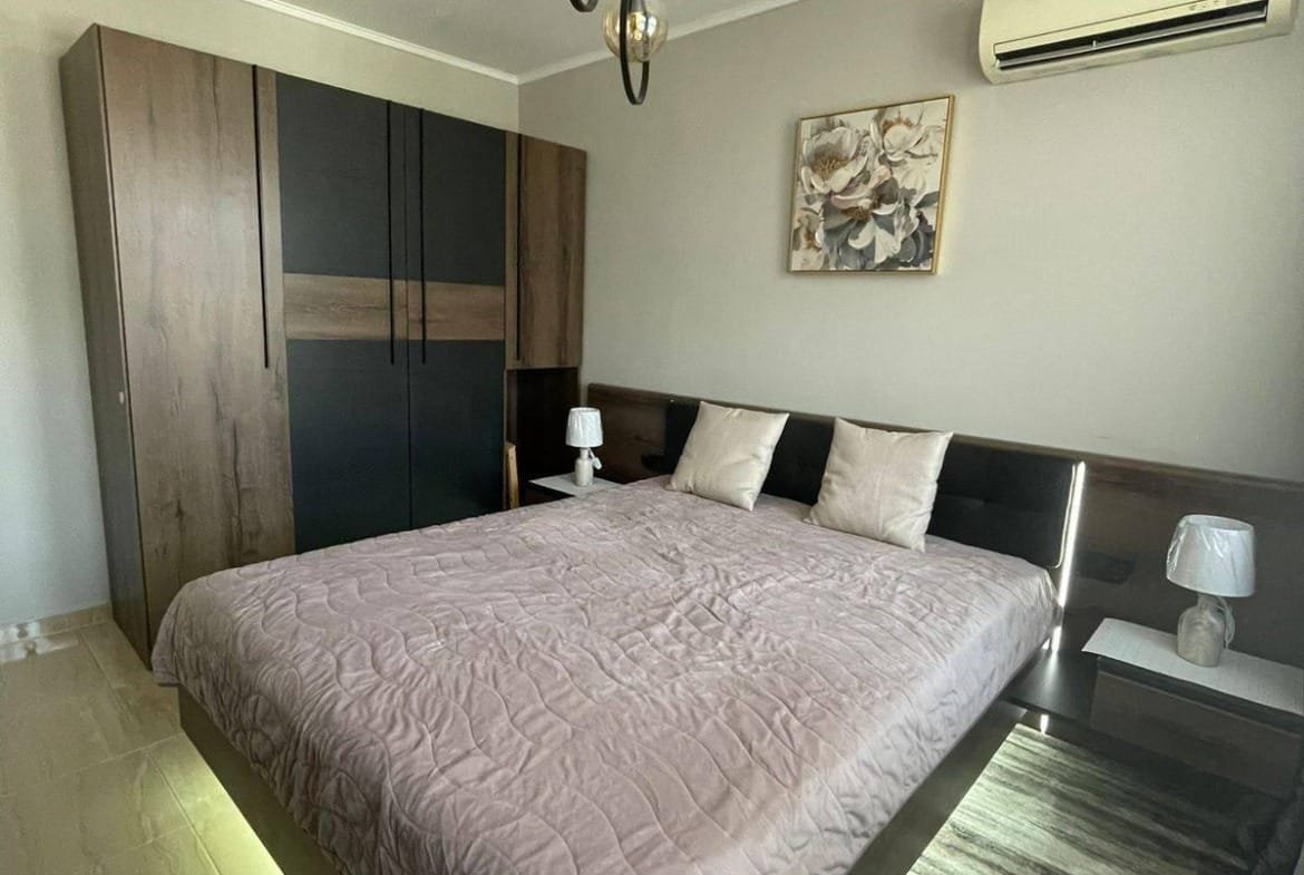 Современная спальня с двуспальной кроватью, стильной мебелью и воздушным освещением, идеально подходит для жизни в Болгарии.