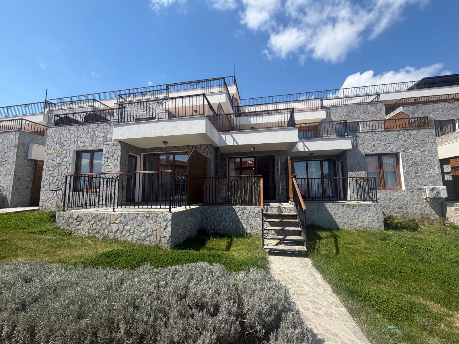 Современный таунхаус с террасой и зелеными насаждениями в Болгарии, идеальный для покупки недвижимости на побережье.