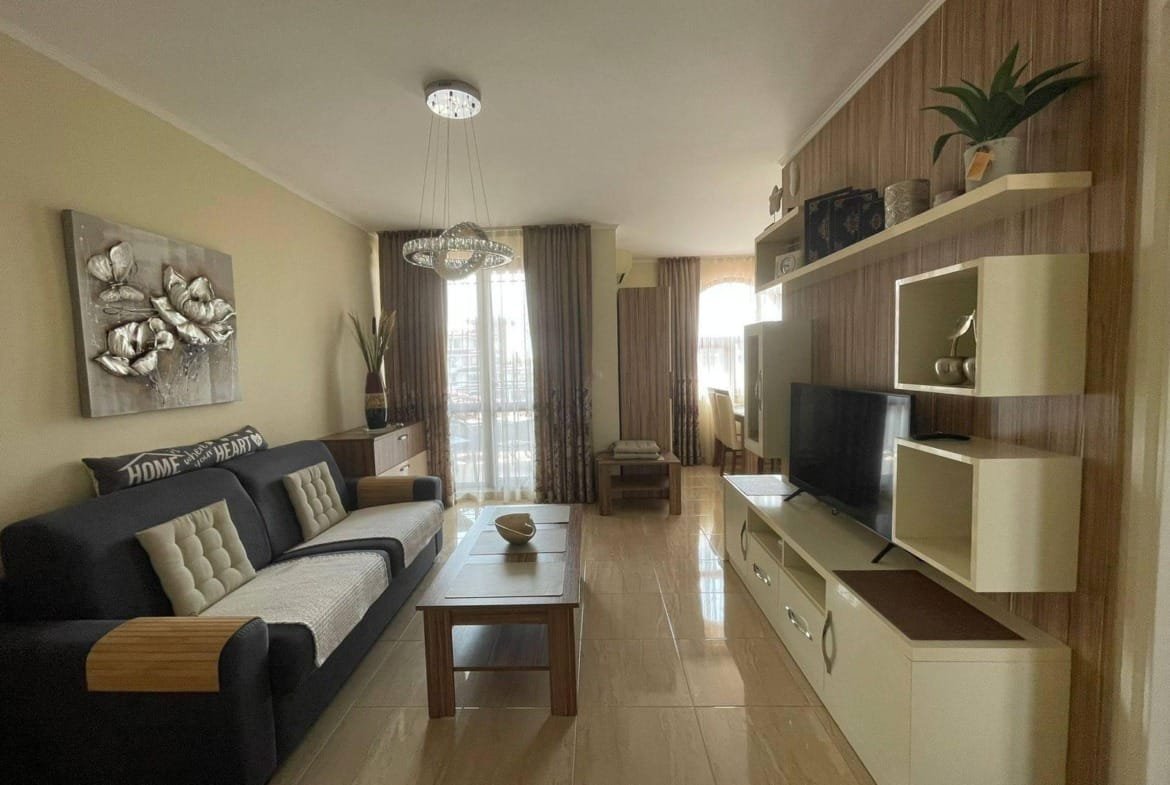 Современная уютная гостиная с телевизором, диваном и стильными элементами декора, подходящая для продажи недвижимости в Болгарии.