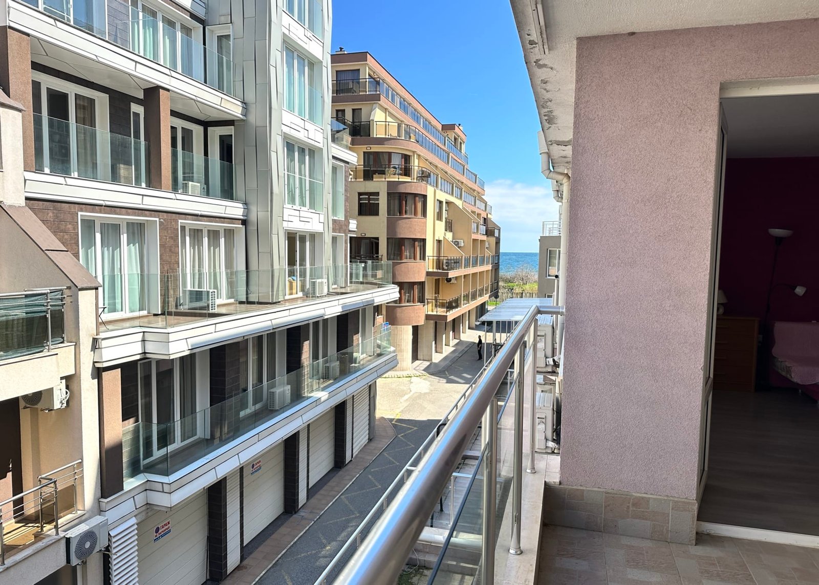 Балкон с видом на современные здания, улицу и голубое небо, отражающие атмосферу жизни в Болгарии.