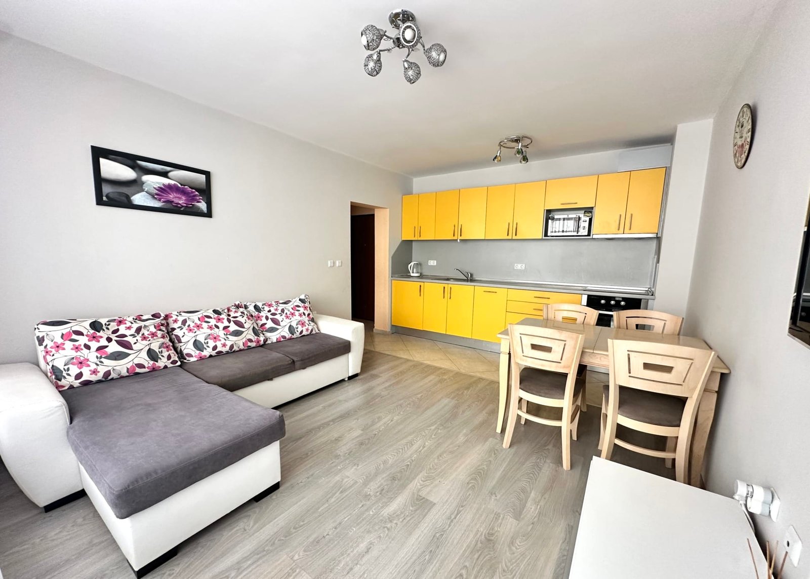 Современная квартира с уютной гостиной, кухней желтого цвета и обеденным столом, идеально подходит для жизни в Болгарии.