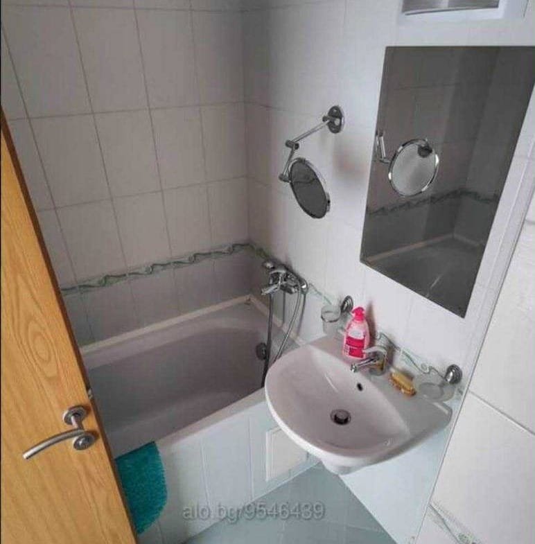 Современная ванная комната с ванной, раковиной и зеркалом в болгарской квартире, готовой к продаже.