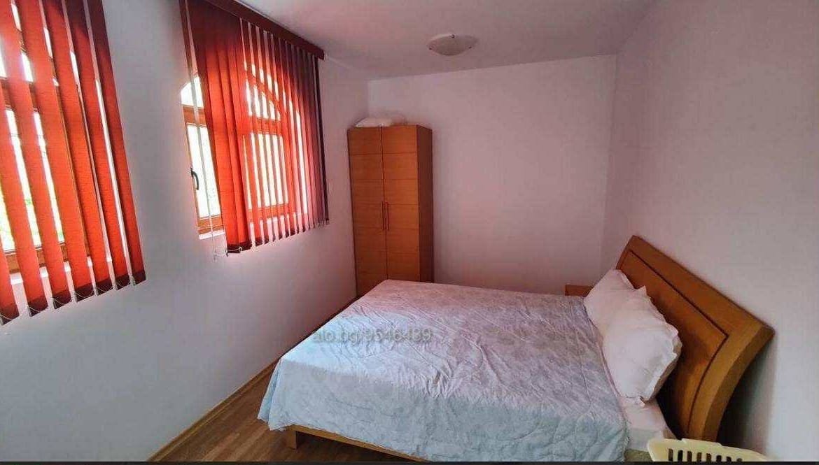 Уютная спальня с кроватью, деревянным шкафом и красными занавесками, идеальная для покупки недвижимости в Болгарии.