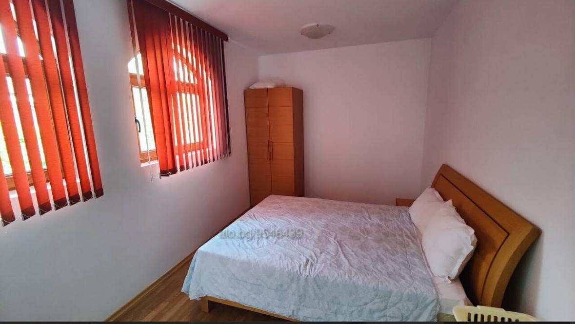 Уютная спальня с кроватью, деревянным шкафом и красными занавесками, идеальная для покупки недвижимости в Болгарии.