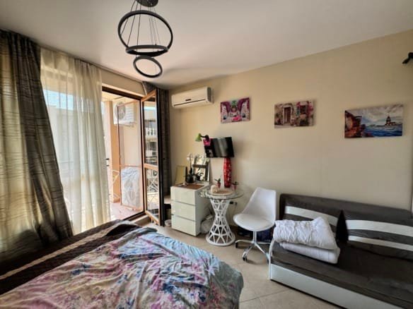 Современный интерьер небольшого номера с двуспальной кроватью, диваном и выходом на балкон в Болгарии.