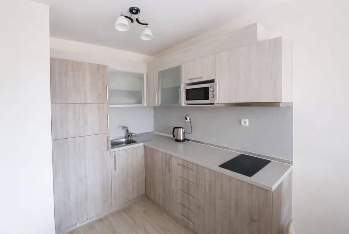 Современная кухня с деревянными шкафами, встроенной плитой и техникой, идеально подходит для покупки недвижимости в Болгарии.