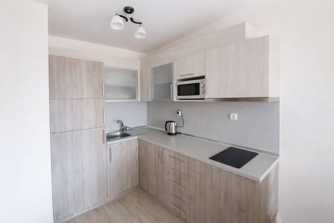 Современная кухня с деревянными шкафами, встроенной плитой и техникой, идеально подходит для покупки недвижимости в Болгарии.