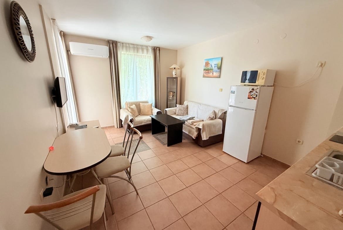 Современная квартира в Болгарии с мебелью, холодильником и столом, идеальная для продаж и аренды недвижимости.