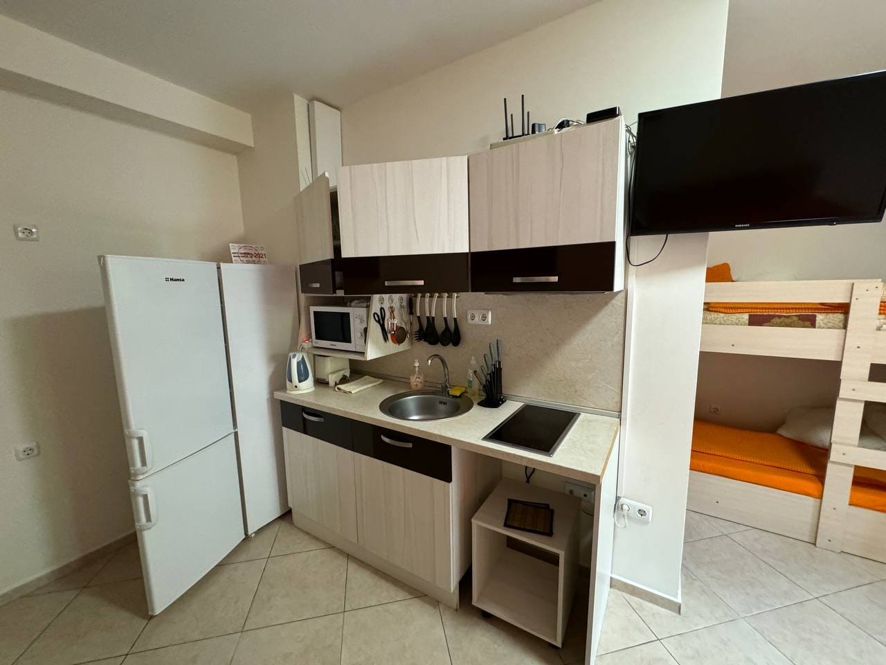 Современная кухня с бытовой техникой, чистыми линиями и светлыми тонами, подходит для аренды недвижимости в Болгарии.