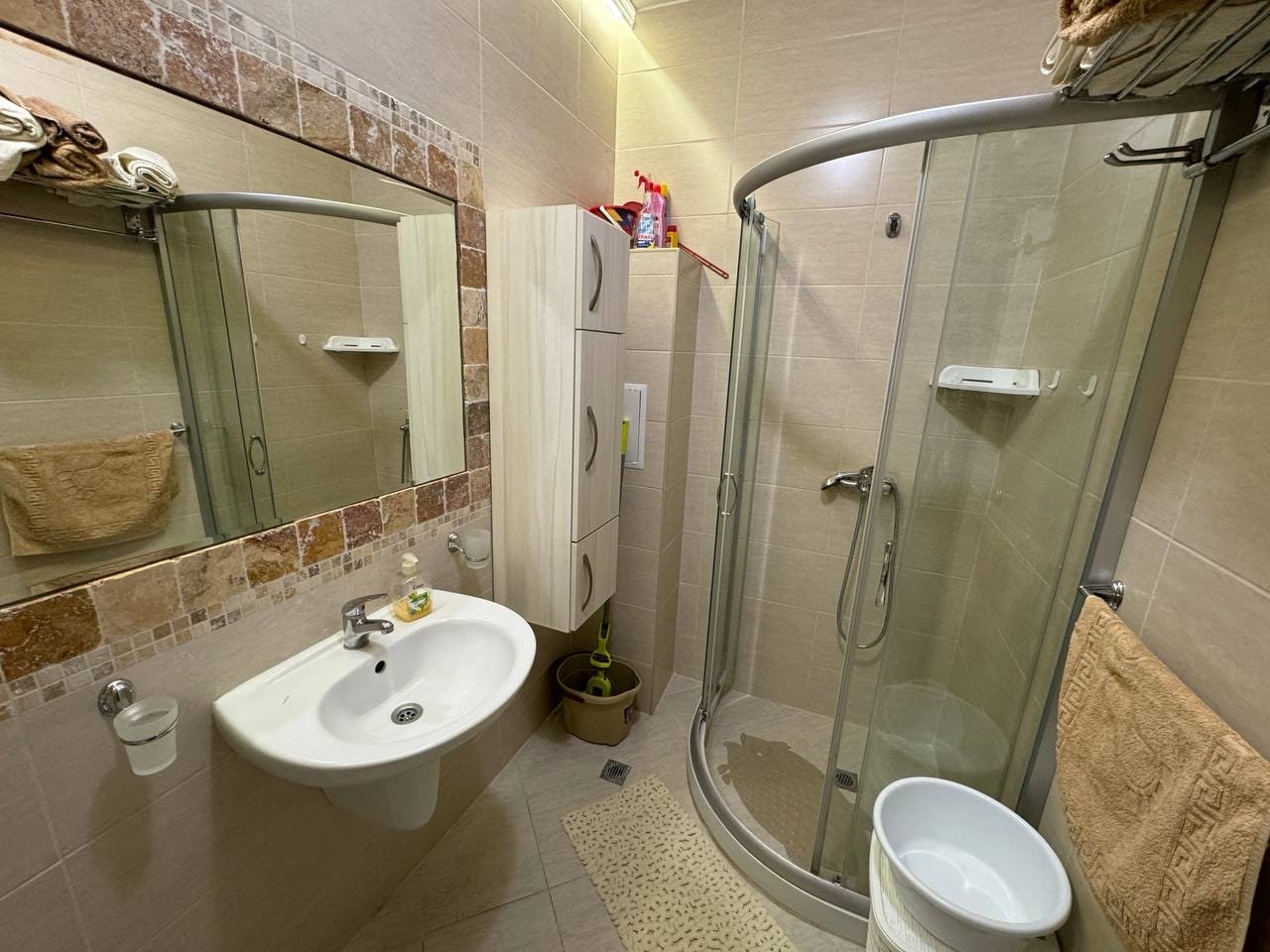 Уютная ванная комната с душевой кабиной, раковиной и зеркалом, отделанная плиткой, идеальная для продажи недвижимости в Болгарии.