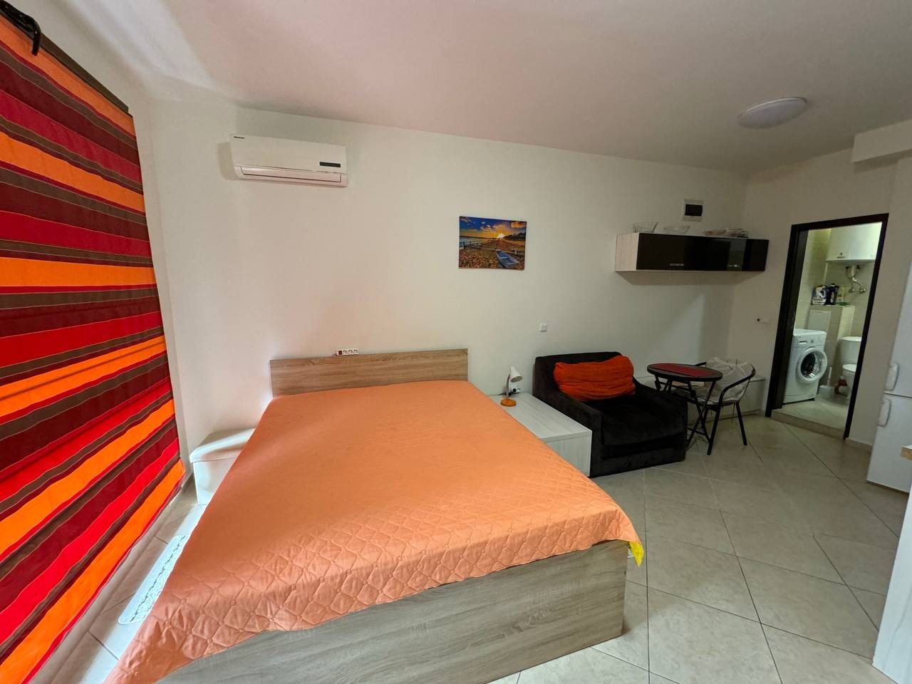 Удобная квартира в Болгарии с одной спальней, диваном и яркими шторами, идеальна для покупки или аренды.