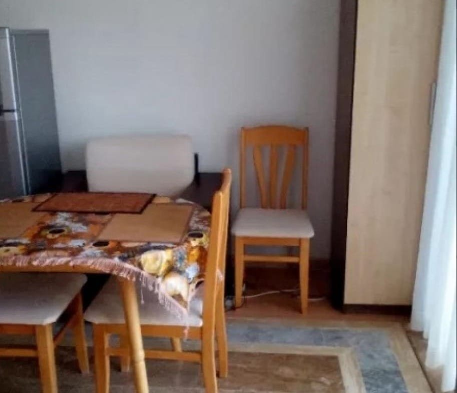 Уютный обеденный уголок в квартире в Болгарии с деревянным столом, стульями и шкафом. Подходит для покупки недвижимости.