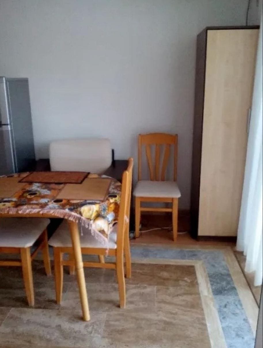 Уютный обеденный уголок в квартире в Болгарии с деревянным столом, стульями и шкафом. Подходит для покупки недвижимости.