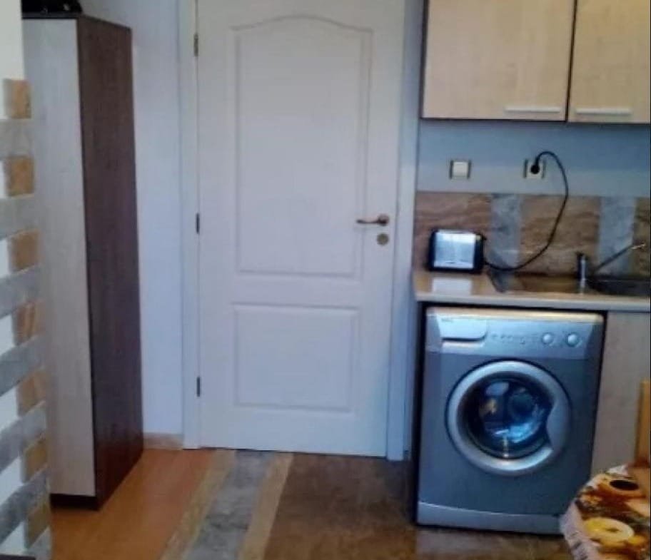 Современная кухня в Болгарии с стиральной машиной, шкафом и столешницей, оформленная в светлых тонах.