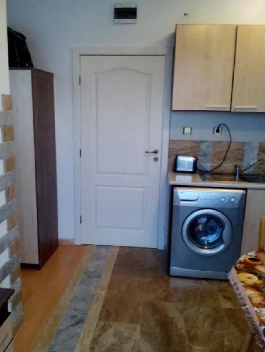 Современная кухня в Болгарии с стиральной машиной, шкафом и столешницей, оформленная в светлых тонах.