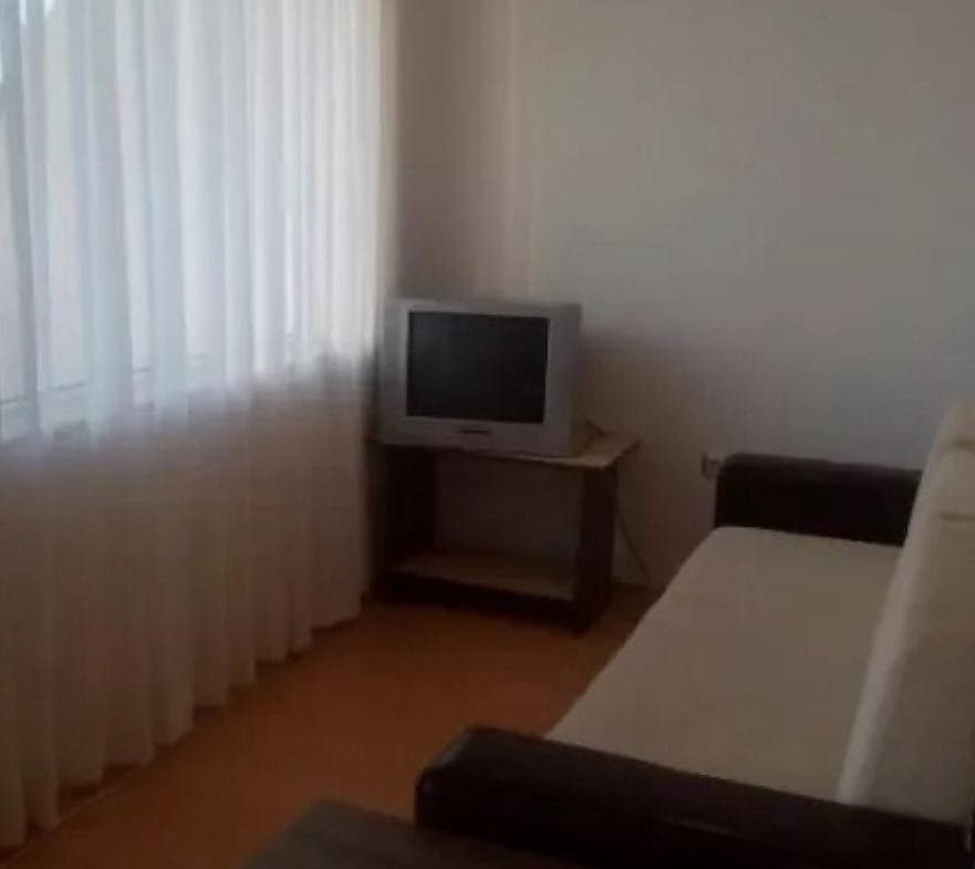 Светлая комната с окном, диваном и телевизором, идеальная для продажи или аренды недвижимости в Болгарии.