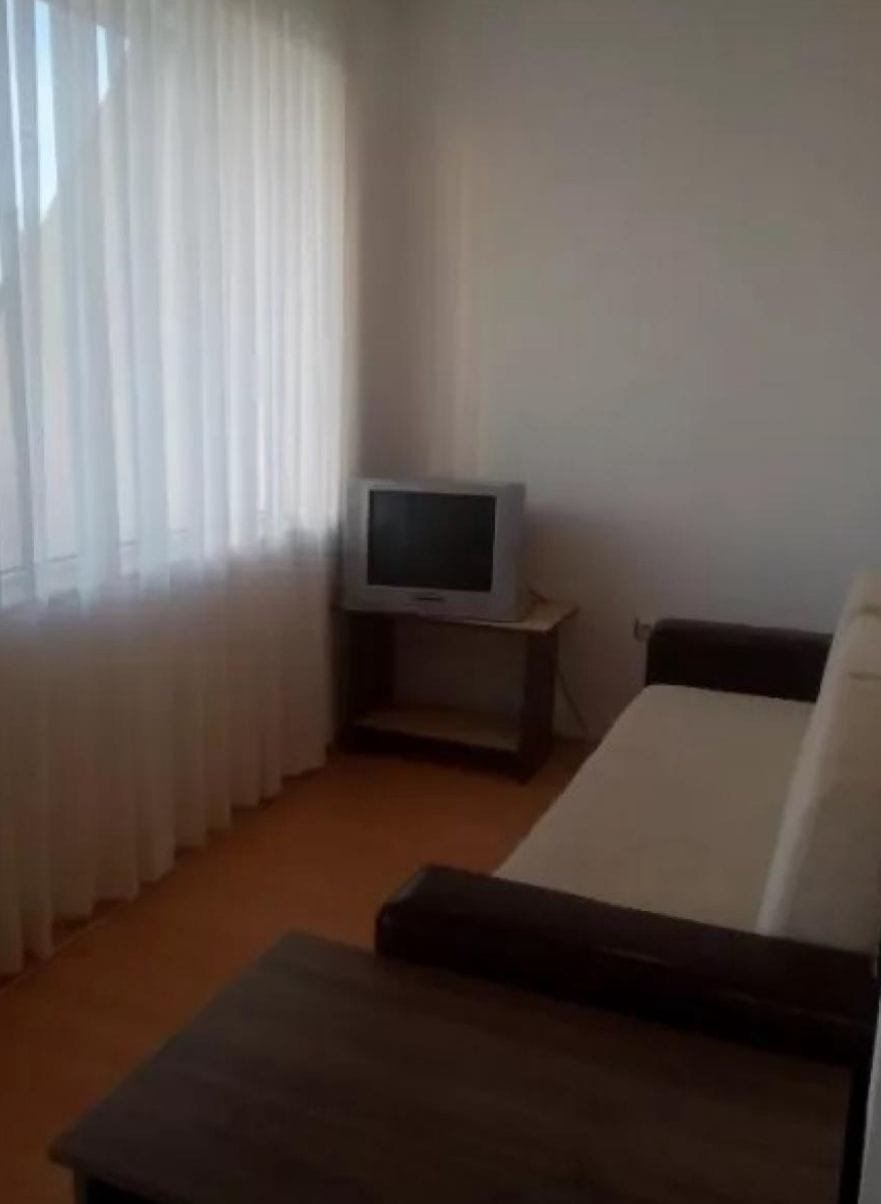 Светлая комната с окном, диваном и телевизором, идеальная для продажи или аренды недвижимости в Болгарии.