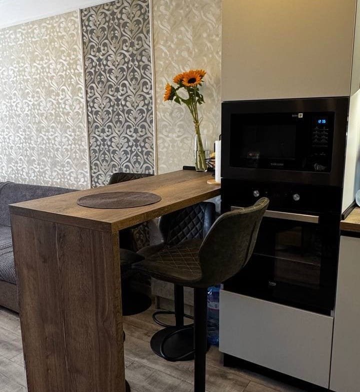 Стильная кухня с барной стойкой, современными приборами и естественными цветами, подходящая для жизни в Болгарии.