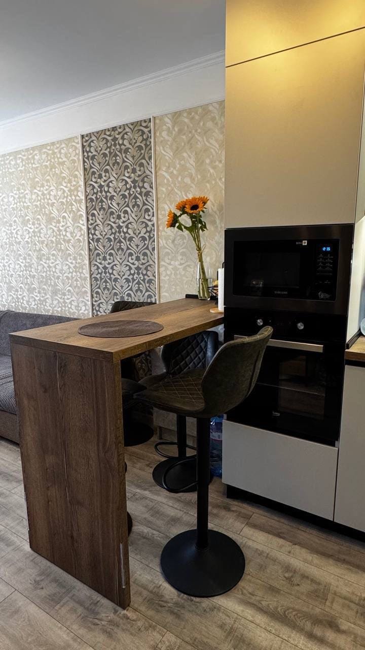 Стильная кухня с барной стойкой, современными приборами и естественными цветами, подходящая для жизни в Болгарии.