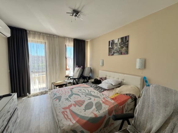 Современная квартира в Болгарии с уютной спальней, светлыми тонами и балконом, идеально подходит для продажи или аренды.