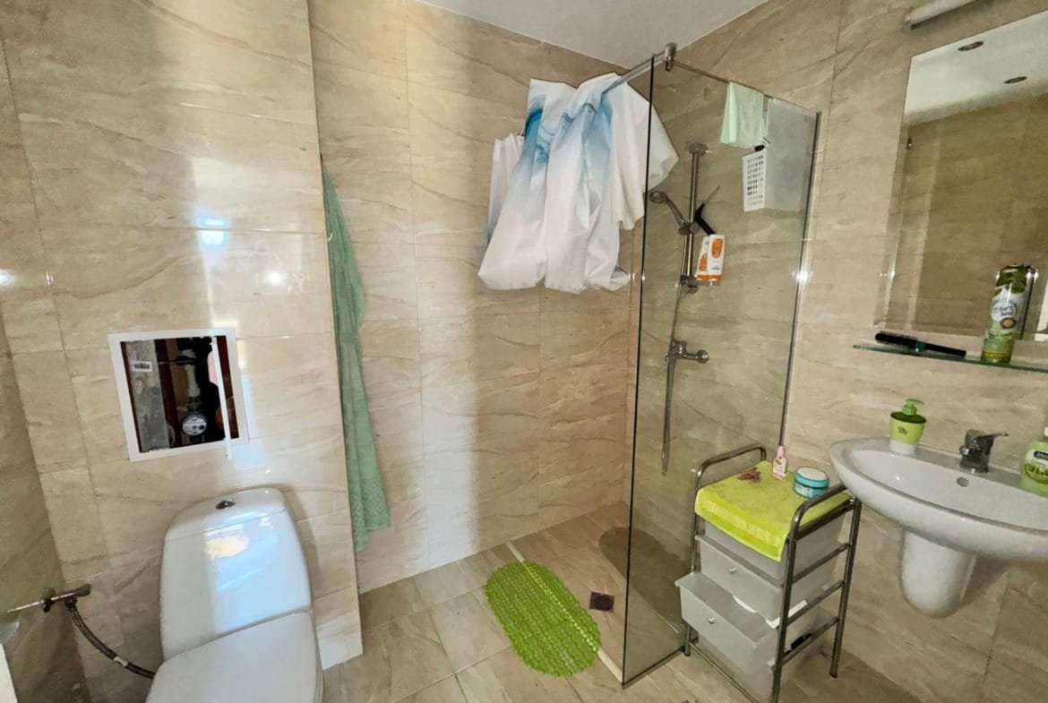 Современная ванная комната с душевой кабиной, туалетом и раковиной, оформленная в светлых тонах для комфортного проживания в Болгарии.