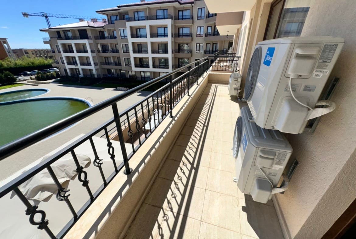 Балкон с кондиционерами, открывающий вид на жилой комплекс и зеленую зону, идеальное место для жизни и инвестиций в Болгарии.