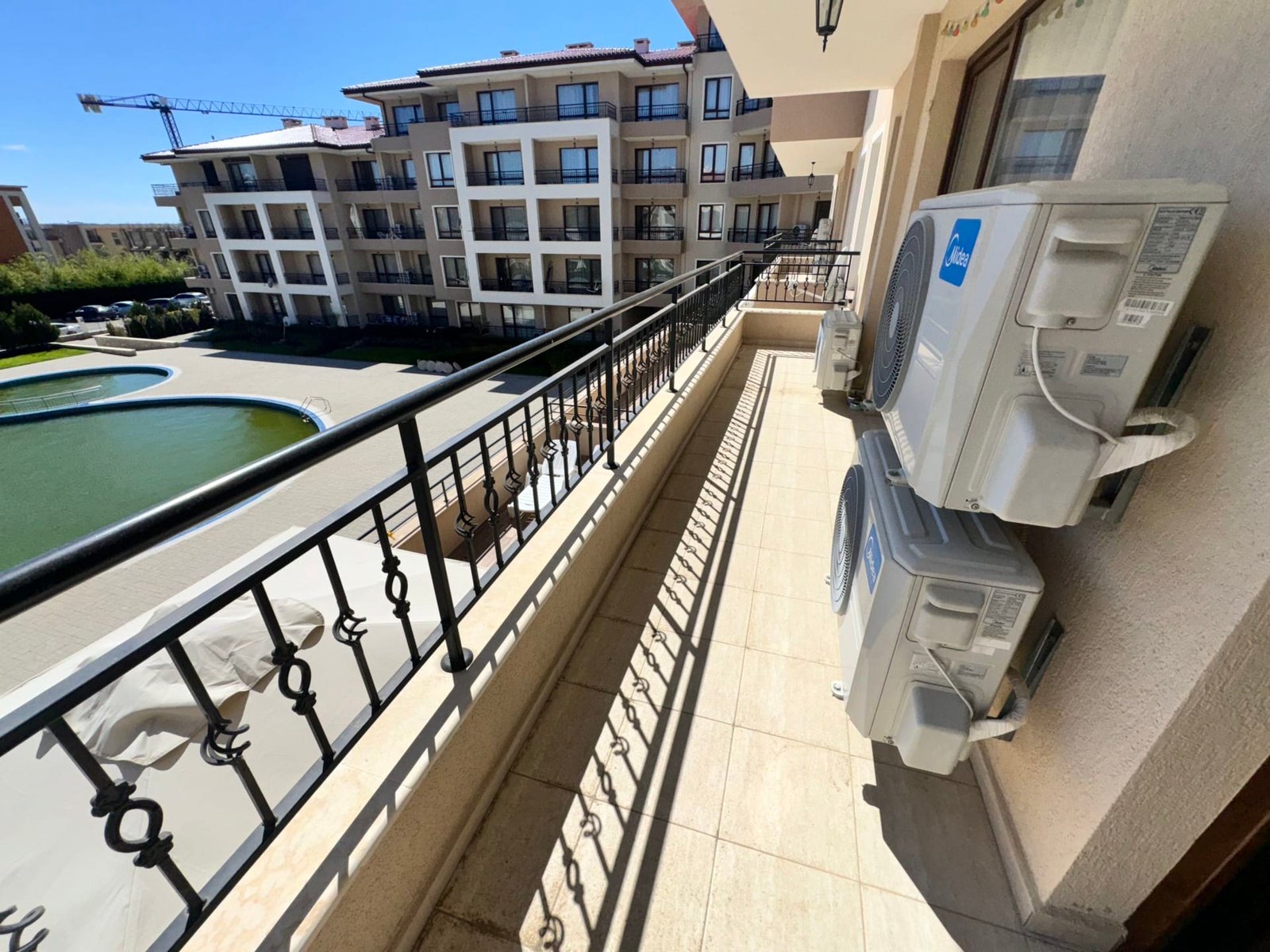 Балкон с кондиционерами и видом на жилой комплекс. Балкон с кондиционерами, открывающий вид на жилой комплекс и зеленую зону, идеальное место для жизни и инвестиций в Болгарии.