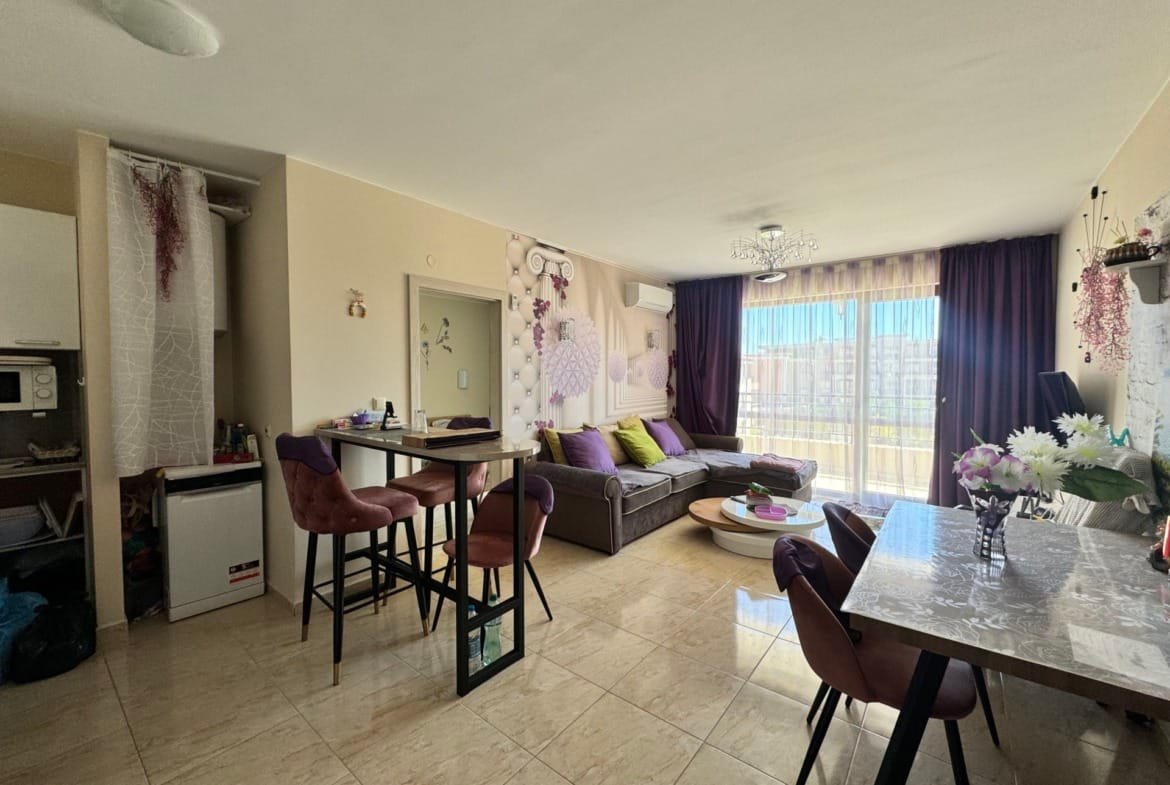 Современная квартира в Болгарии с светлым интерьером, зоной отдыха и обеденной зоной, открывающей вид на улицу.