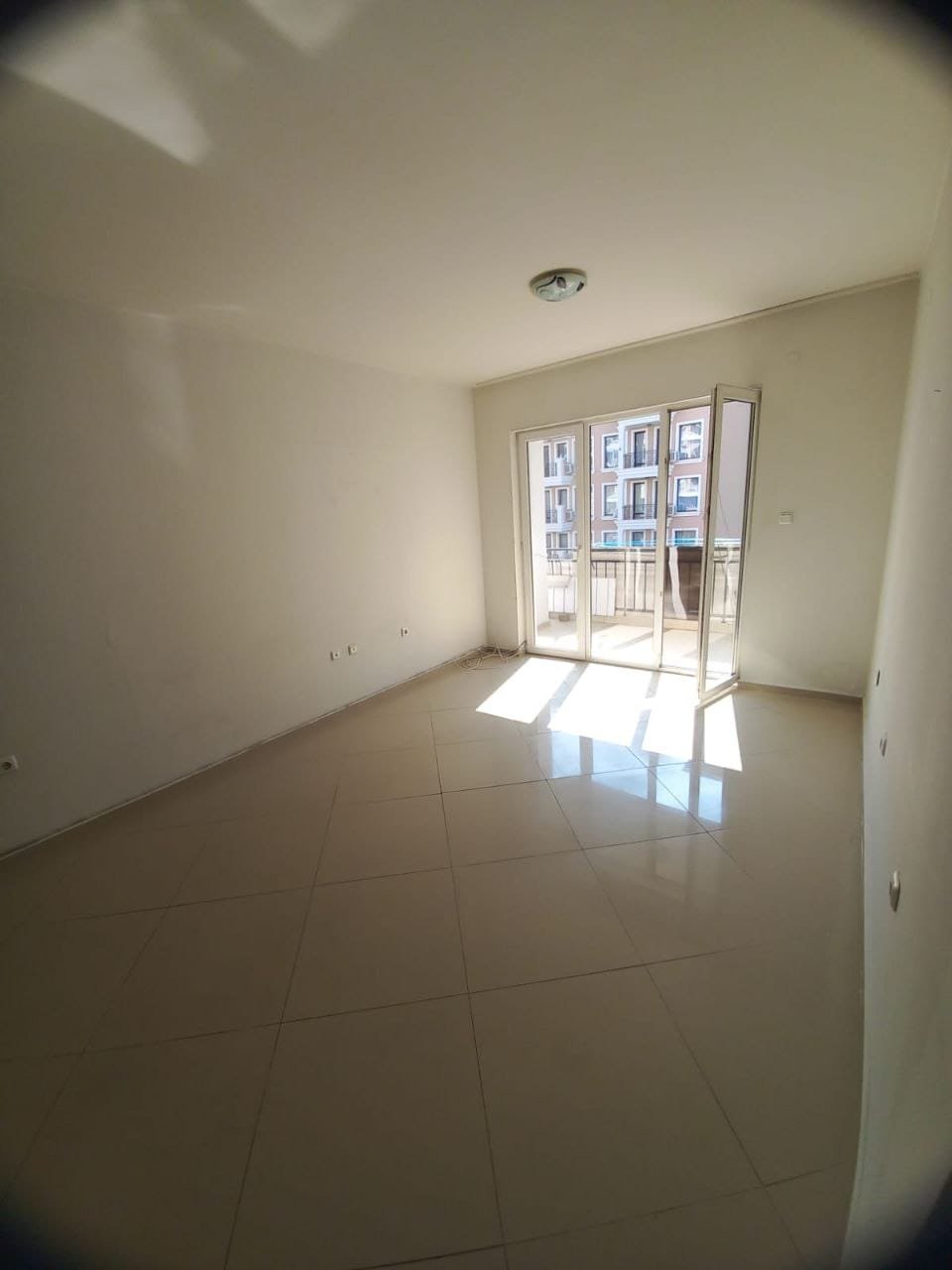 Светлая квартира с балконом и большими окнами. Светлая комната с большими окнами, панорамный вид на улицу, идеальное предложение для покупки недвижимости в Болгарии.