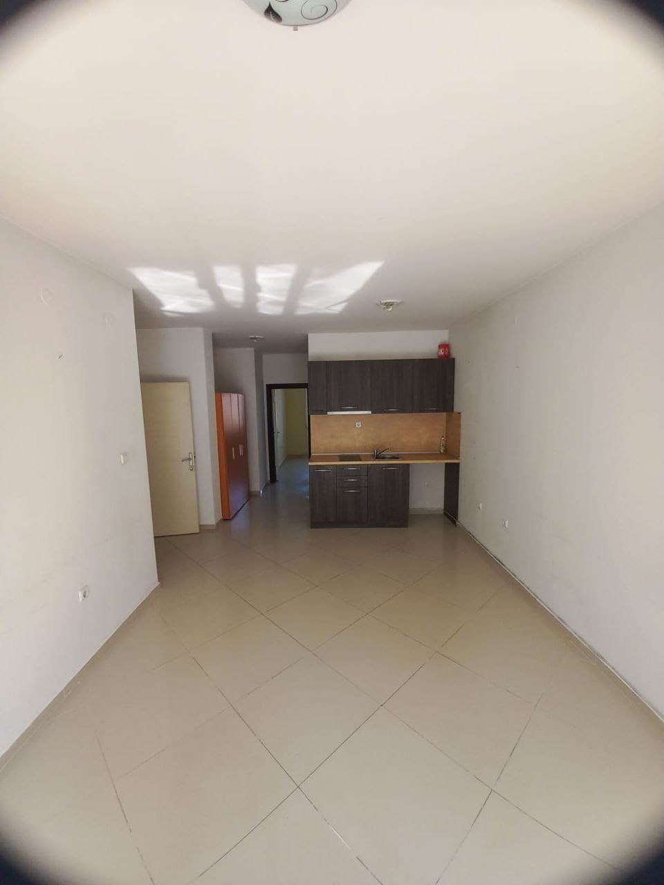 Современный интерьер пустой квартиры с кухонным уголком Светлая квартира в Болгарии с открытой планировкой, плиточным полом и кухонным уголком, готовая для продажи или аренды.