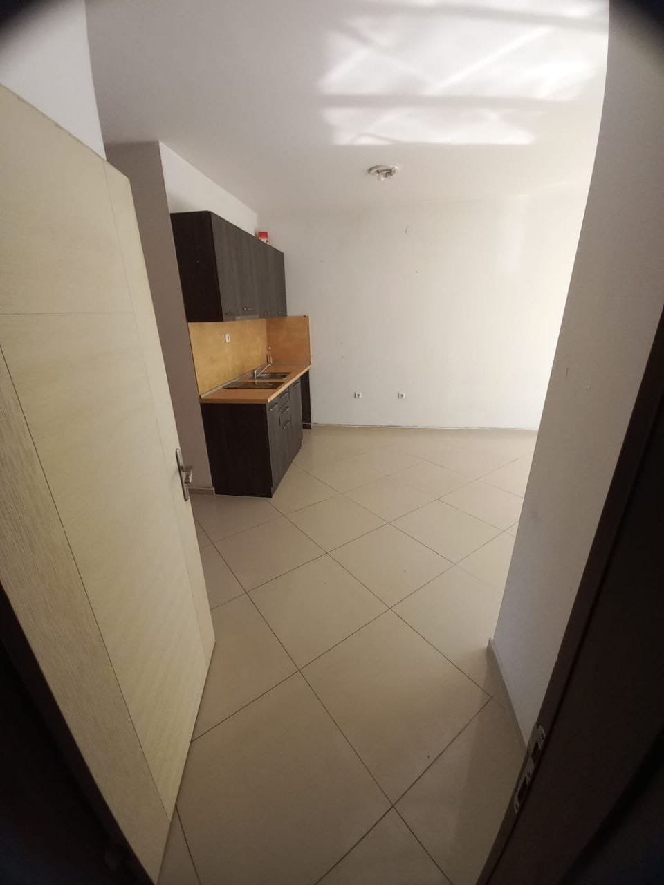 Современная кухня в пустой квартире с плиткой и шкафами Современная кухня в квартире в Болгарии, светлые стены, плиточный пол, местом для размещения бытовой техники.