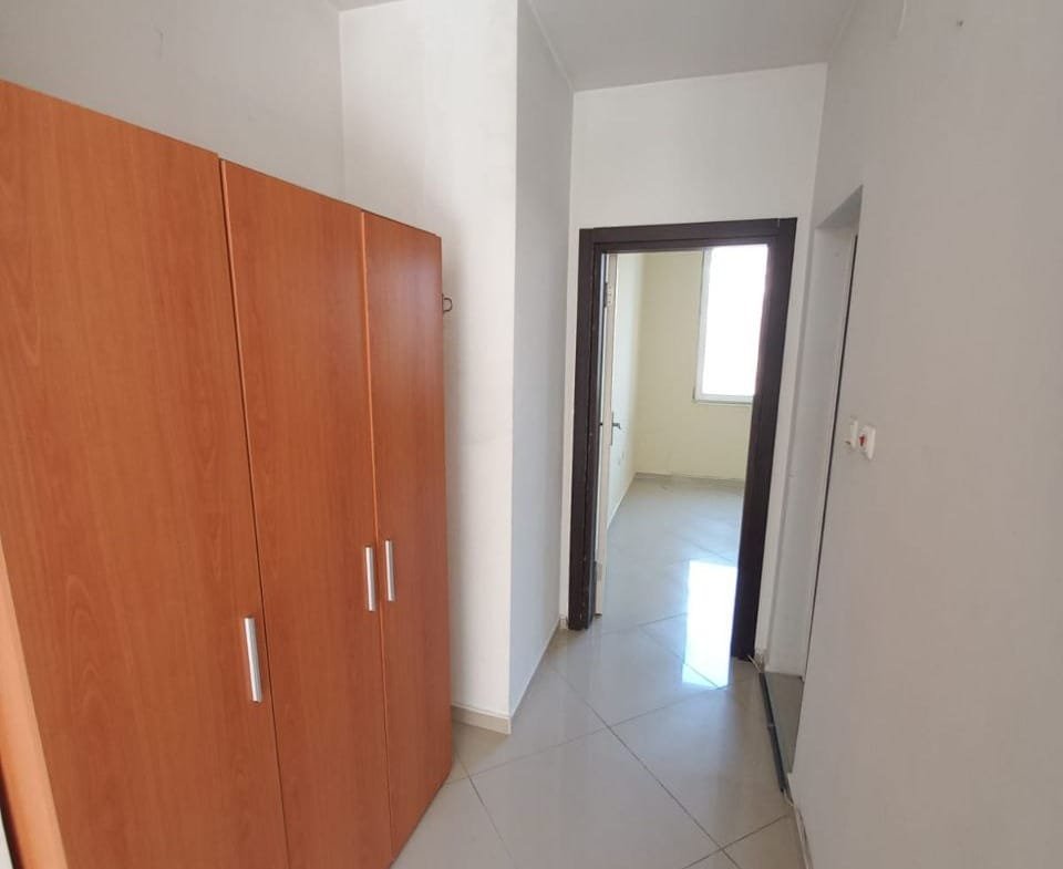 Современный коридор с деревянным шкафом, плиточным полом и светлыми стенами, идеально подходящий для покупки недвижимости в Болгарии.