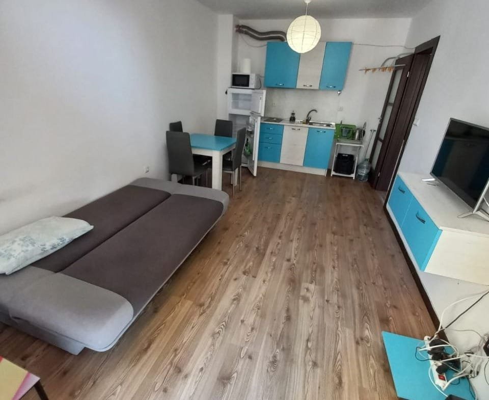 Современная квартира в Болгарии с открытой планировкой, кухней в голубых тонах и уютной зоной для отдыха.