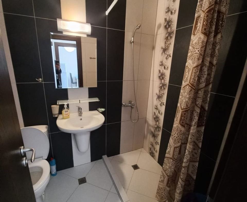 Современная ванная комната с душевой кабиной, унитазом и раковиной, оформленная в черно-белых тонах, подходит для жилья в Болгарии.