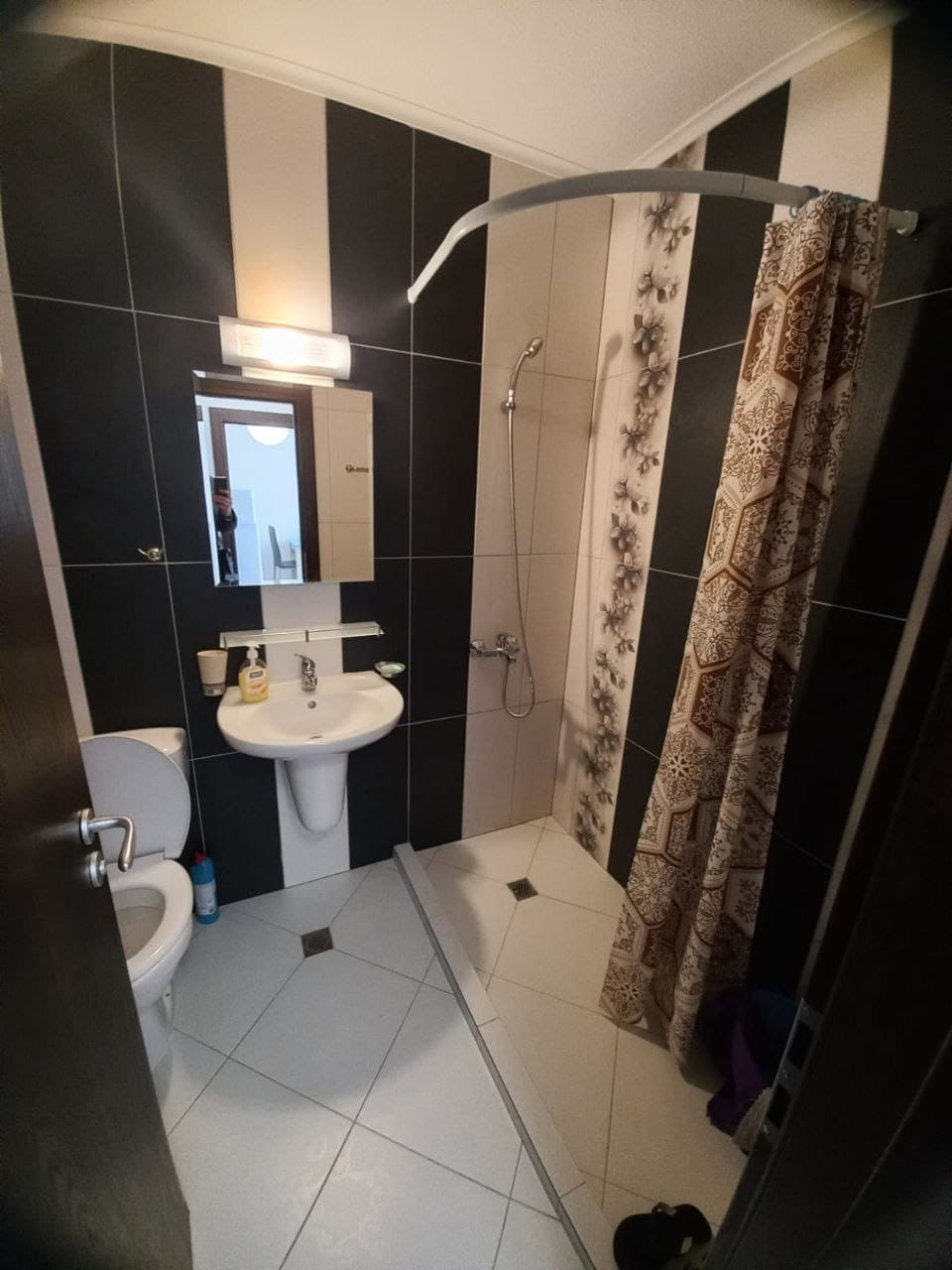 Современная ванная комната с душем и туалетом Современная ванная комната с душевой кабиной, унитазом и раковиной, оформленная в черно-белых тонах, подходит для жилья в Болгарии.