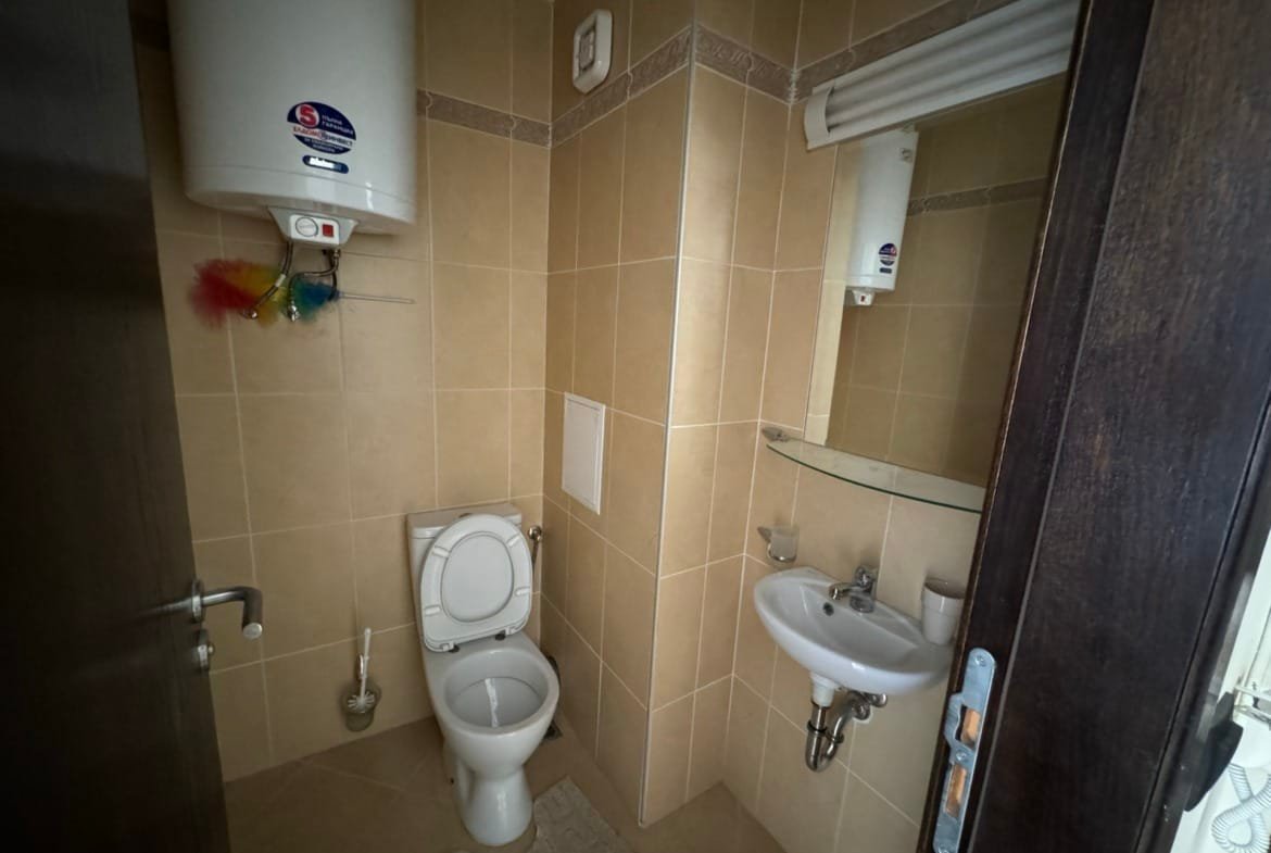 Санузел с сантехникой, кафельной плиткой и зеркалом, идеальный для покупки недвижимости в Болгарии.