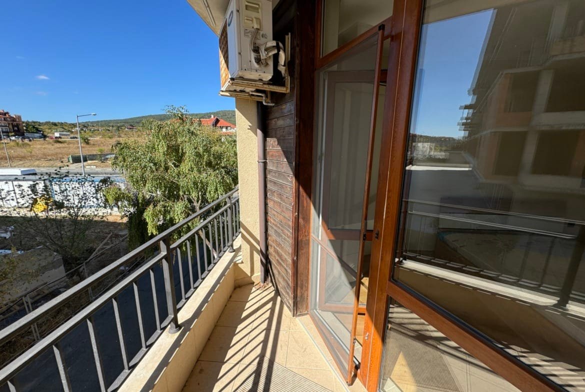 Балкон с стеклянной дверью, открывающей вид на окрестности, идеальное место для покупки недвижимости в Болгарии.